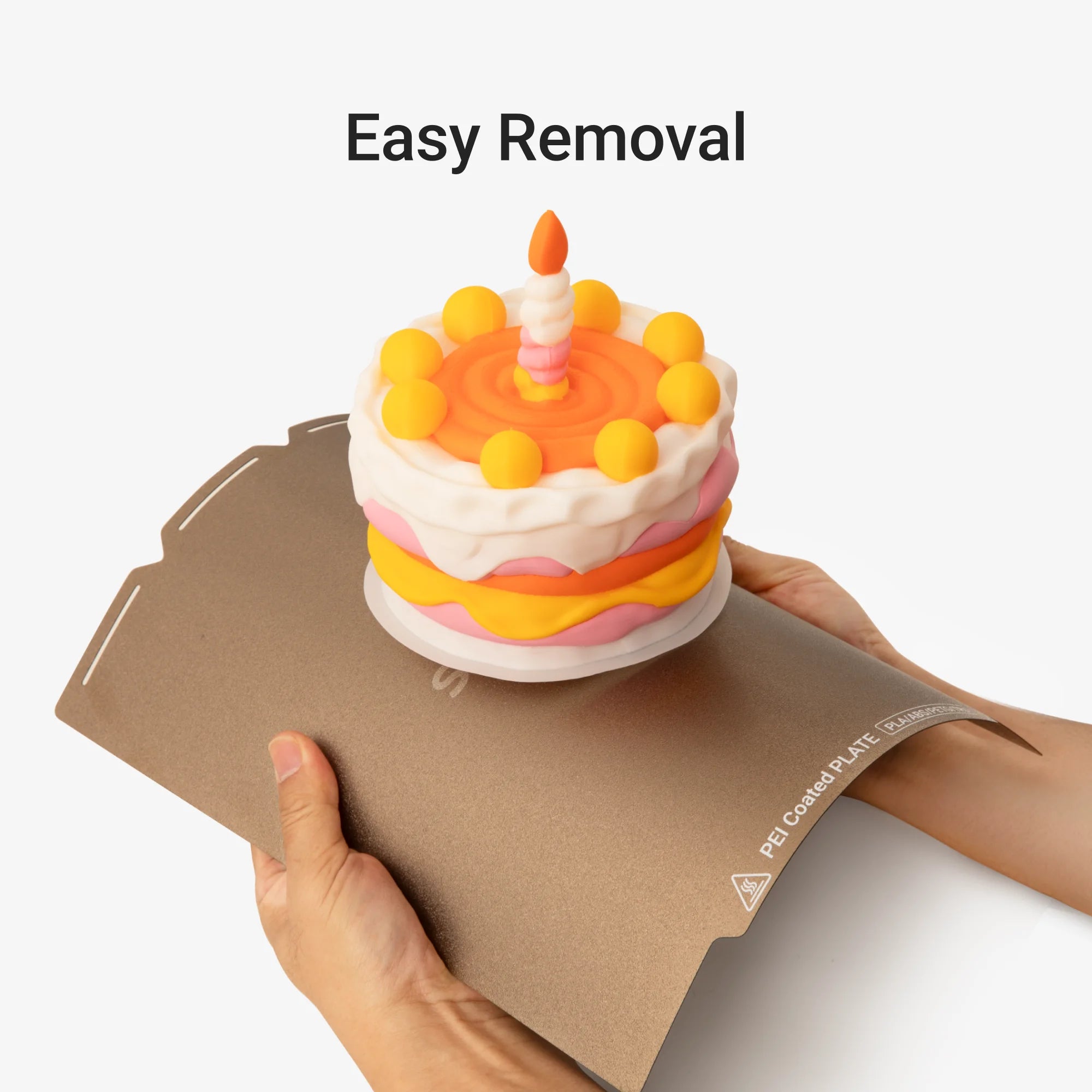 Textured PEI Steel Plate for Snapmaker U1 flexes beneath a 3D-printed cake, demonstrating easy model removal.